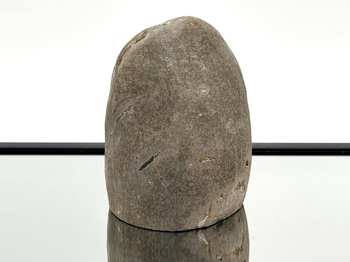 Large Uruguayan Amethyst Crystal Geode (AMU33) displayed on a reflective surface, showcasing its polished sides.