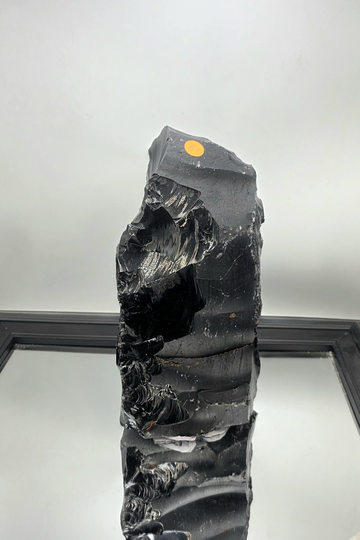 Freeform black obsidian crystal used as a dramatic dining table centerpiece in a contemporary space.