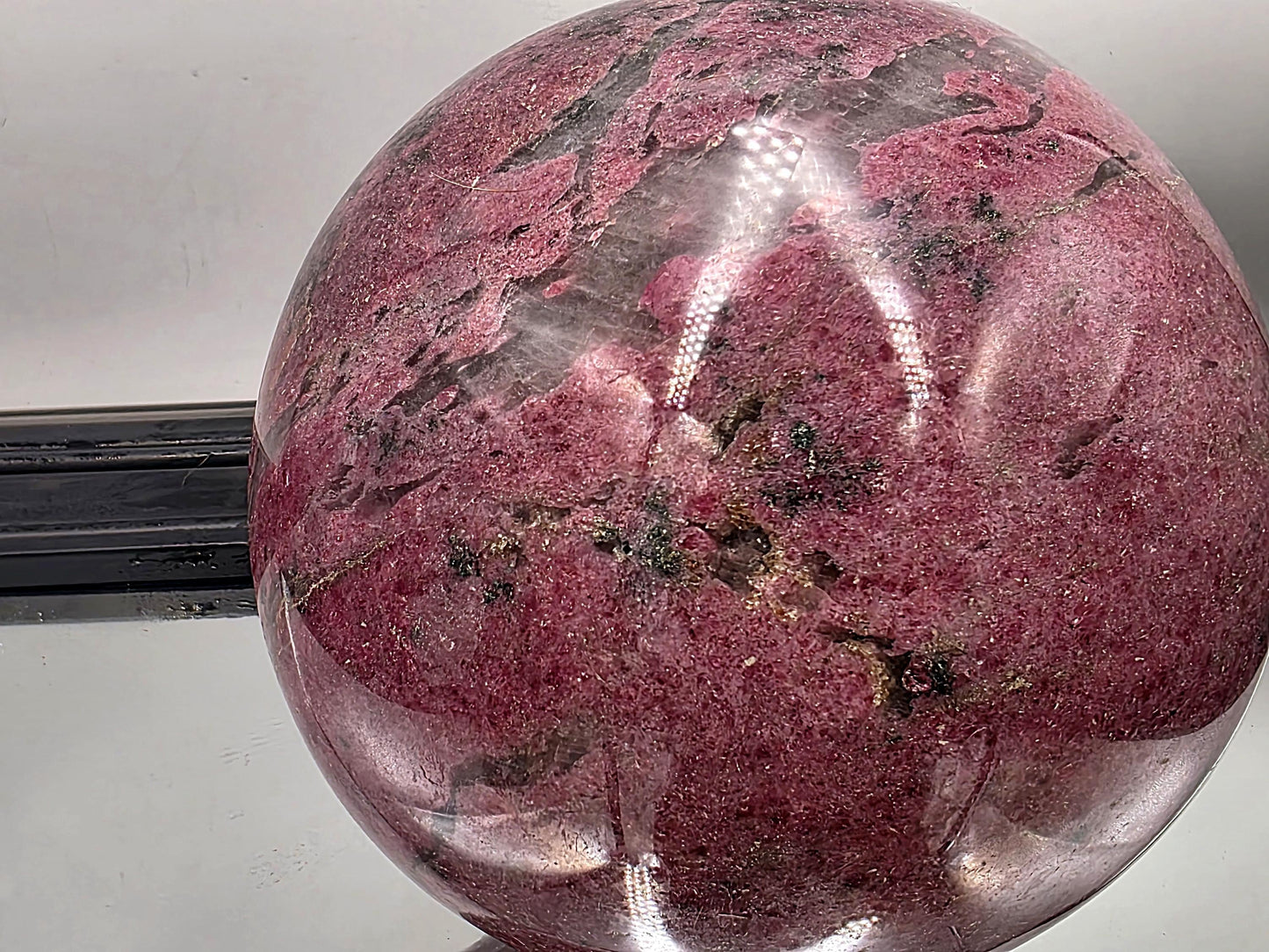 Eye-catching polished rhodonite sphere in natural stone tones.