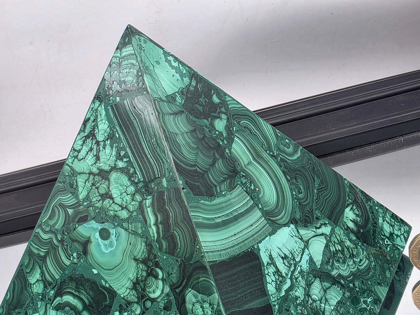 Oversized malachite pyramid featured in a luxurious living room as a sculptural centerpiece.