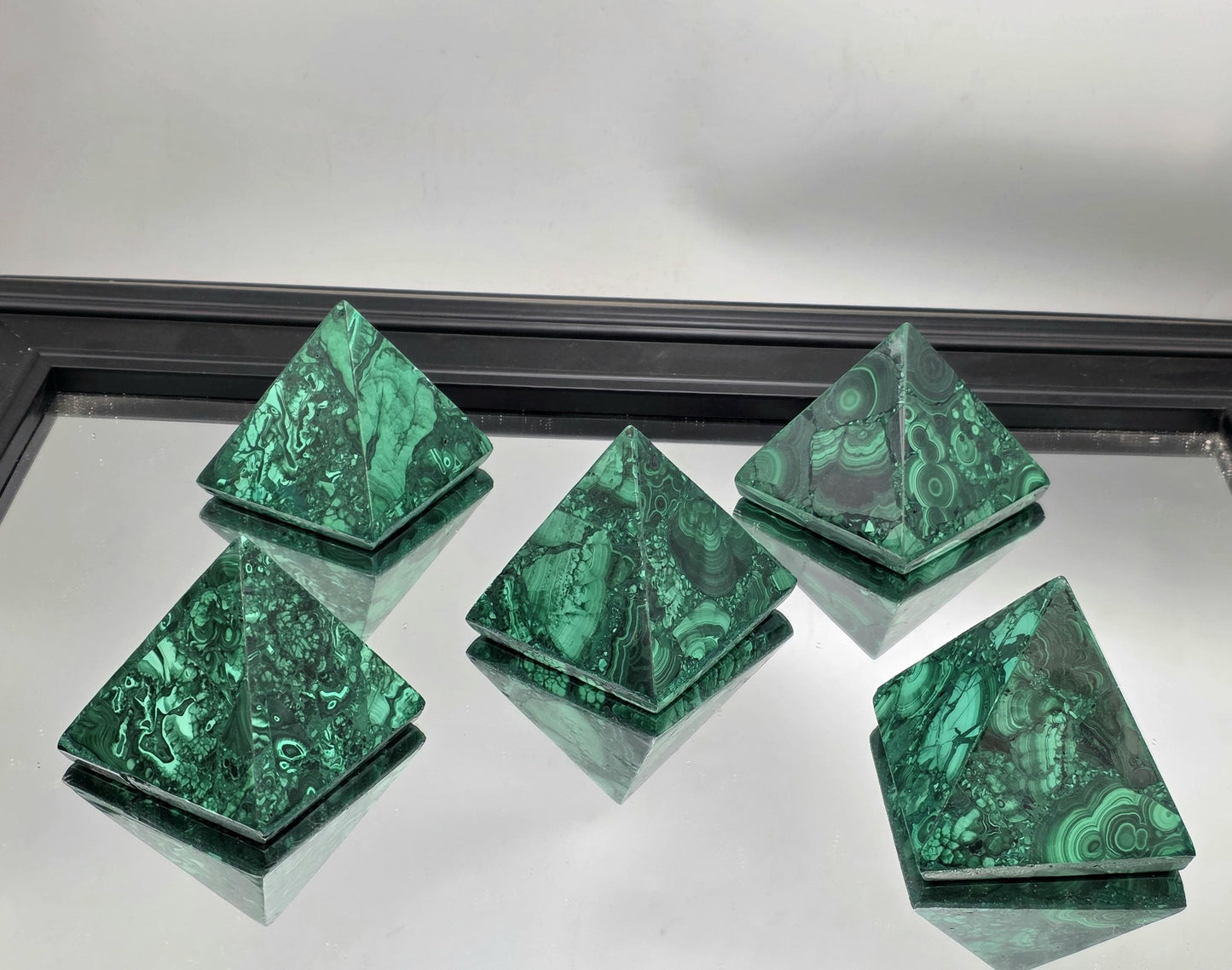 Large malachite crystal pyramid enhancing a luxury interior with organic geometry.