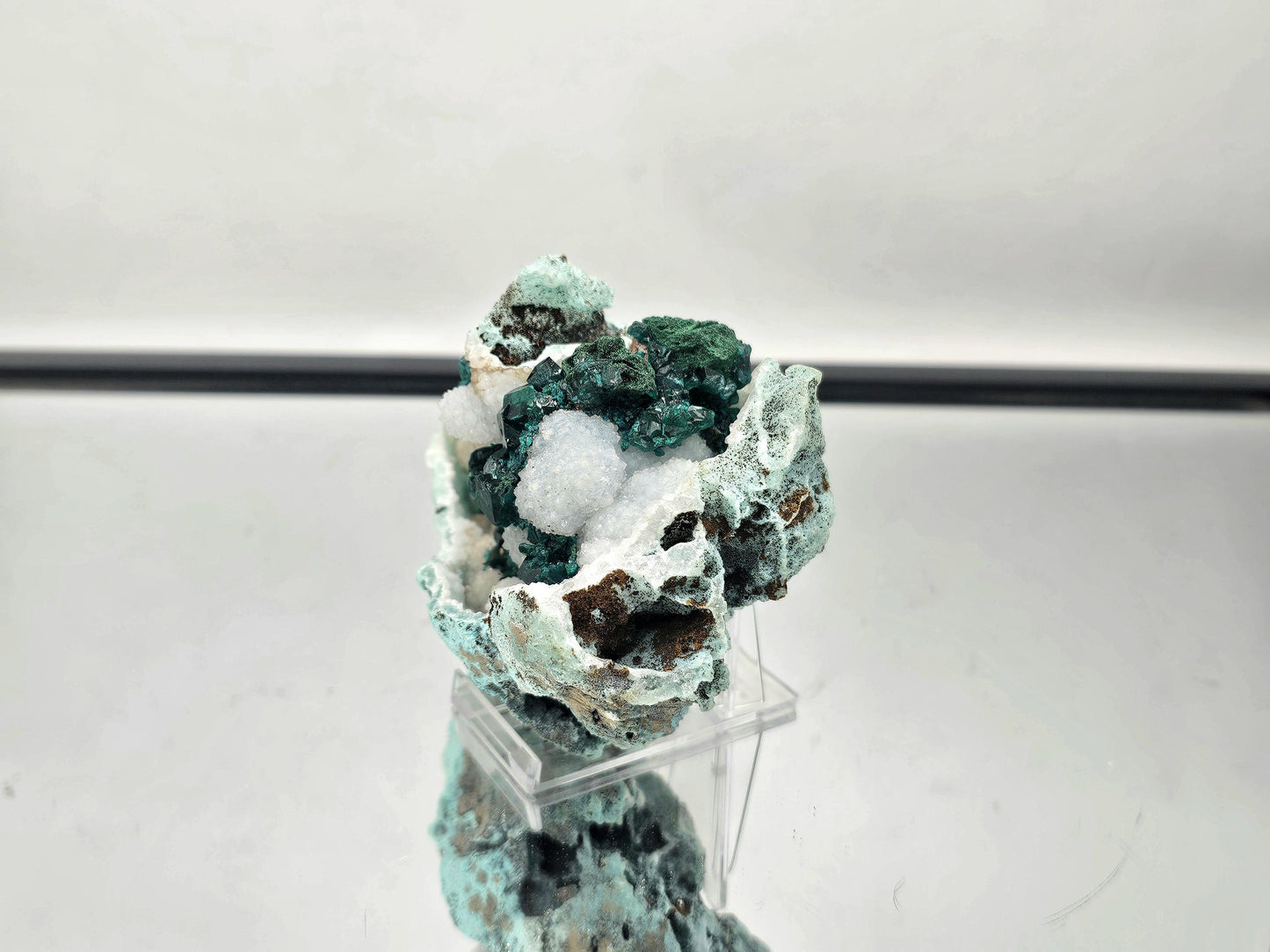 ioptase on Quartz matrix, highlighting the intricate crystalline details and vivid green color.