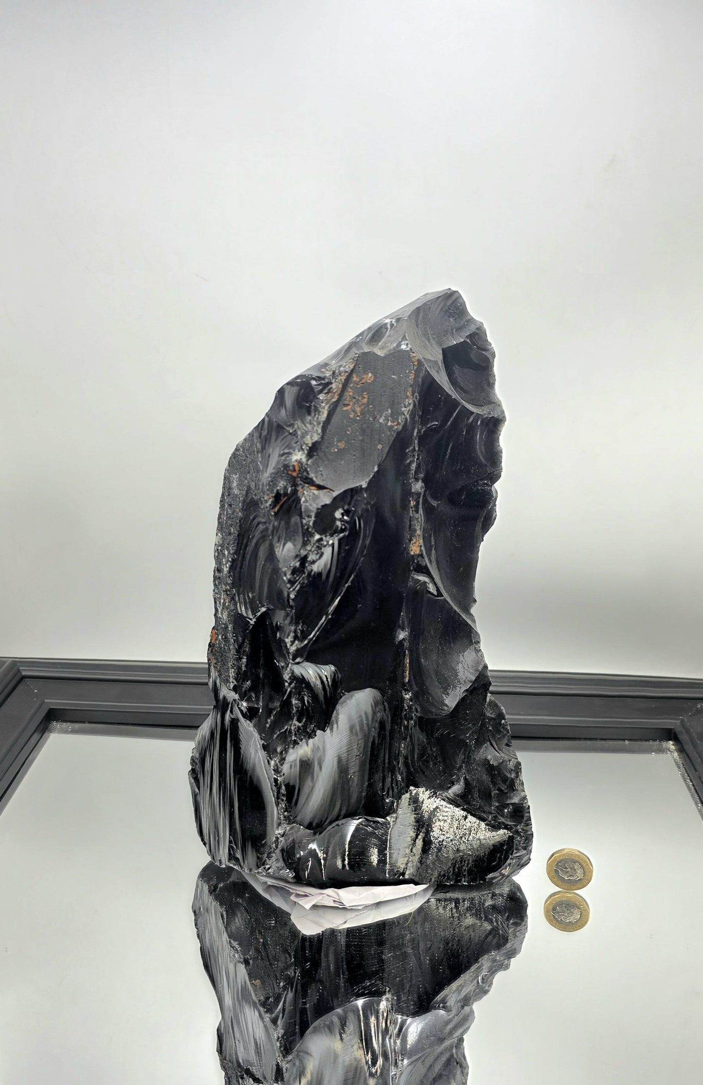 Polished black obsidian crystal featured on a coffee table with curated interior accents.