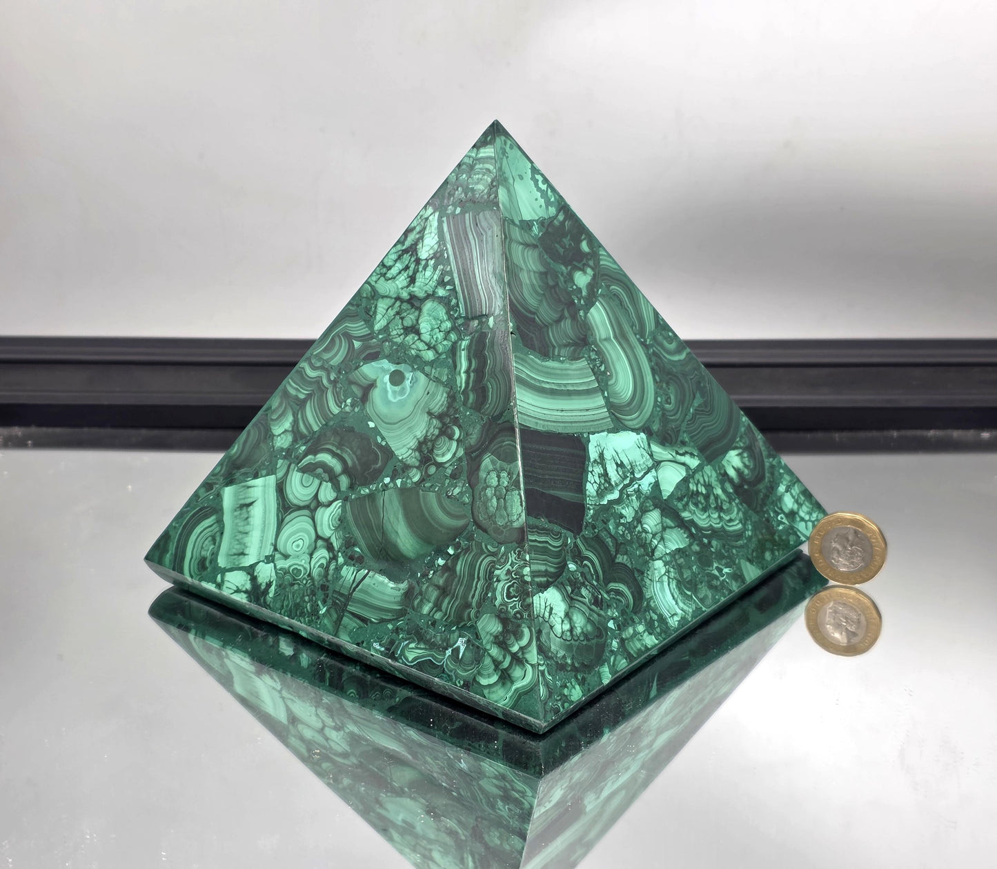Large and extra large malachite pyramids arranged on an open shelf for layered natural style.