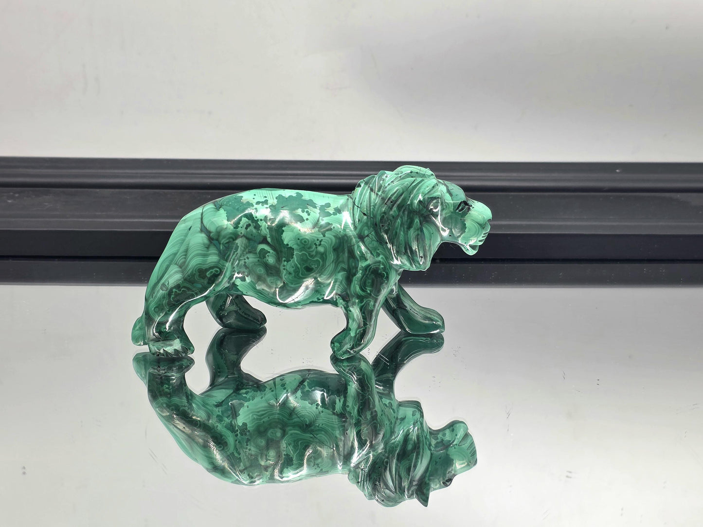 Bold malachite tiger carving displayed on a modern wooden console table.