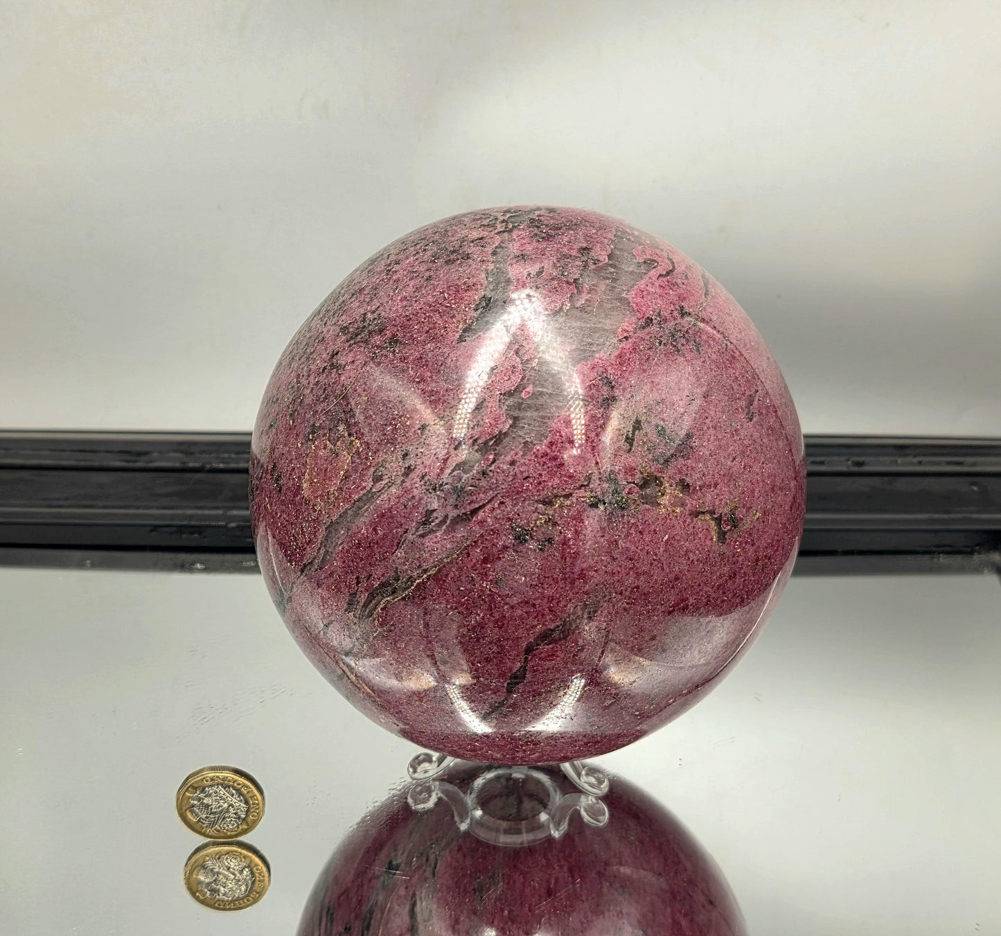 Showpiece-quality rhodonite sphere with rich matrix contrast.