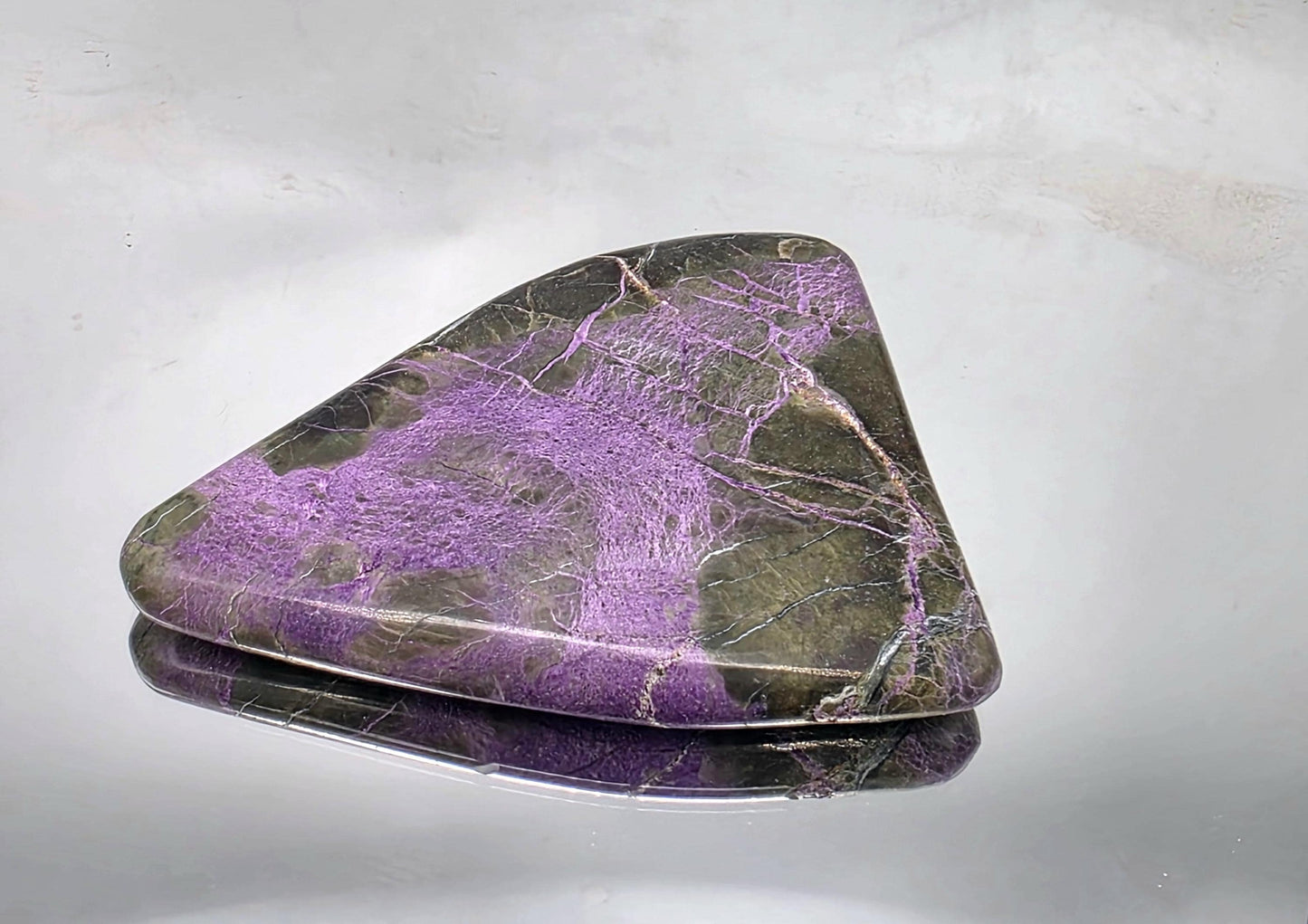 Handheld crystal with a polished surface, showing vivid colors.