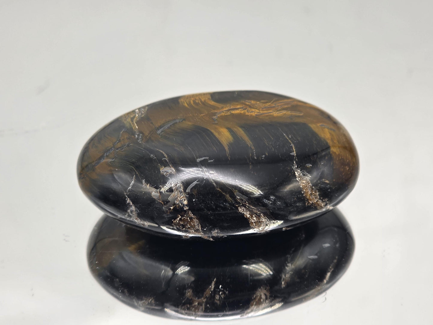 A smooth, polished Tiger’s Eye palmstone sized perfectly for handheld use.