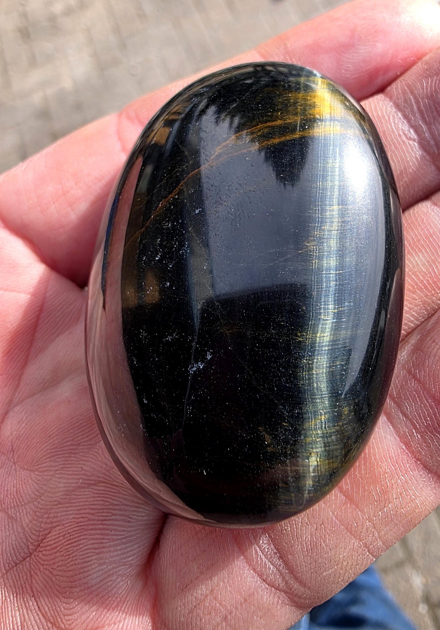 A polished, pocket-sized Tiger’s Eye stone with natural beauty.