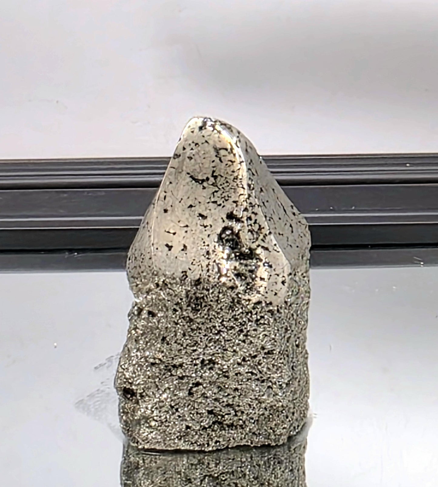 Large pyrite crystal point with metallic shimmer and cubic form.