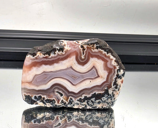 Polished Moroccan agate slice with pink, lavender, and black banding.