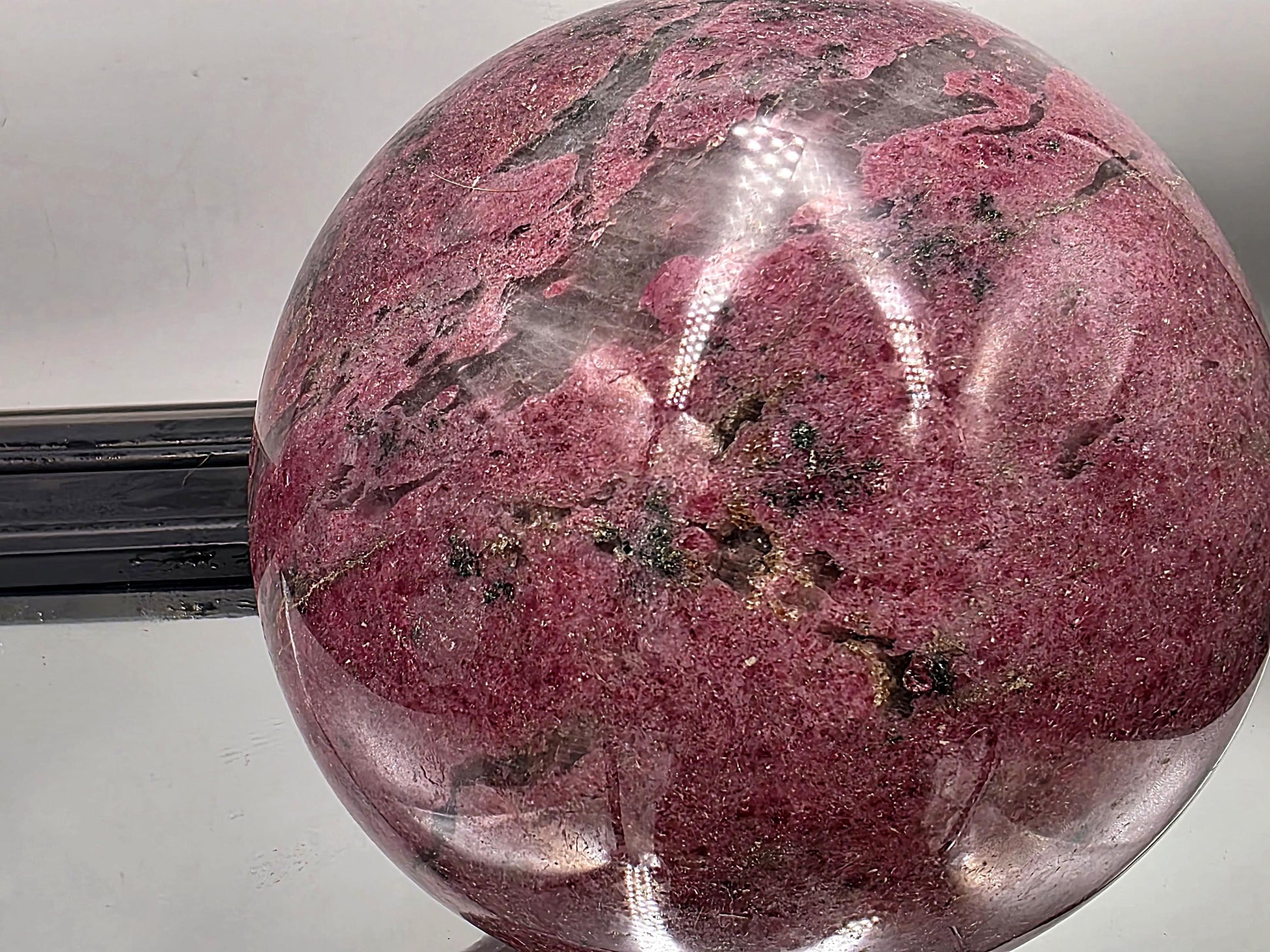 Eye-catching polished rhodonite sphere in natural stone tones.