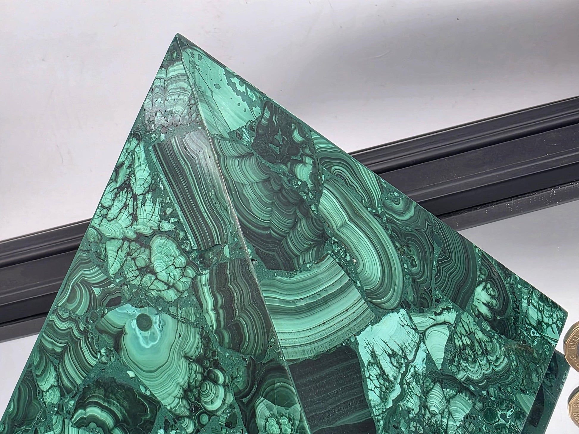 Oversized malachite pyramid featured in a luxurious living room as a sculptural centerpiece.