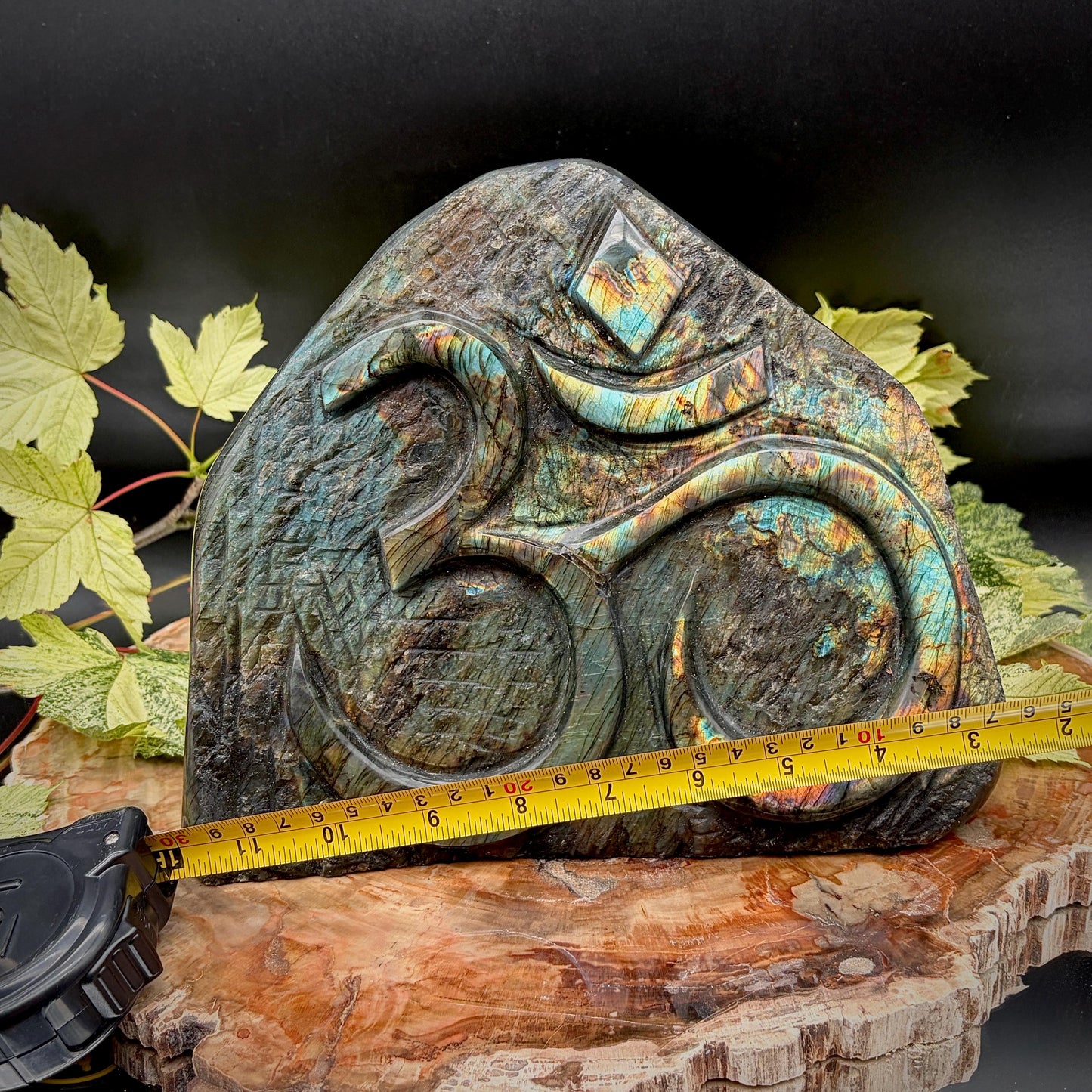 Close-up of the intricately hand-carved Om symbol on exceptional grade Labradorite.