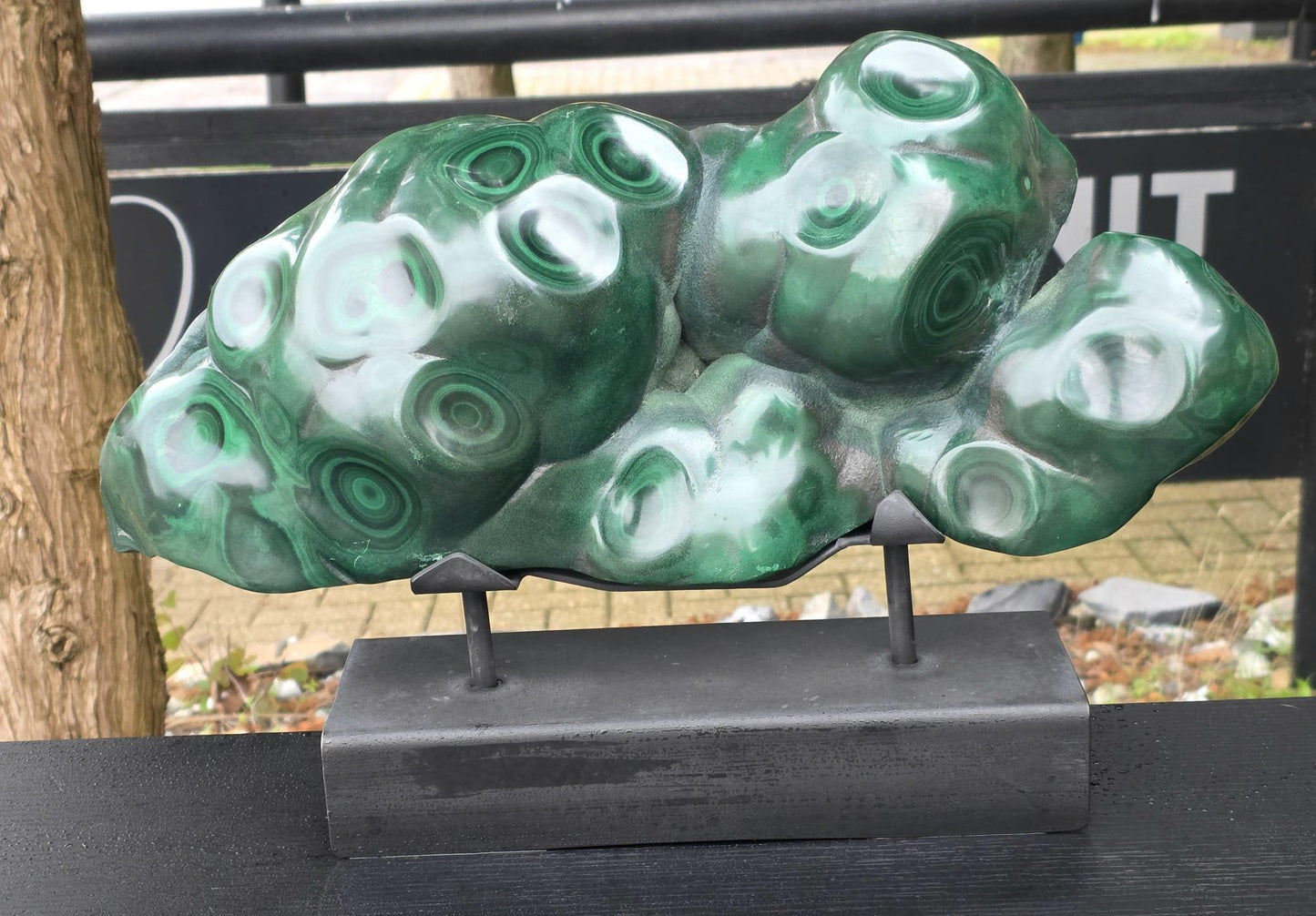 Large polished Malachite sculpture displayed in luxury interior setting