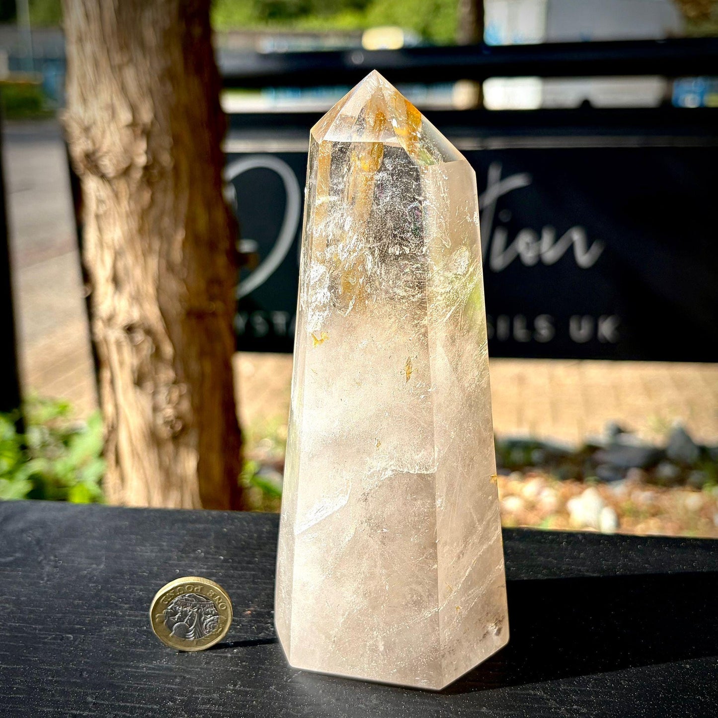 Large polished quartz crystal point with natural inclusions and decorative display presence.