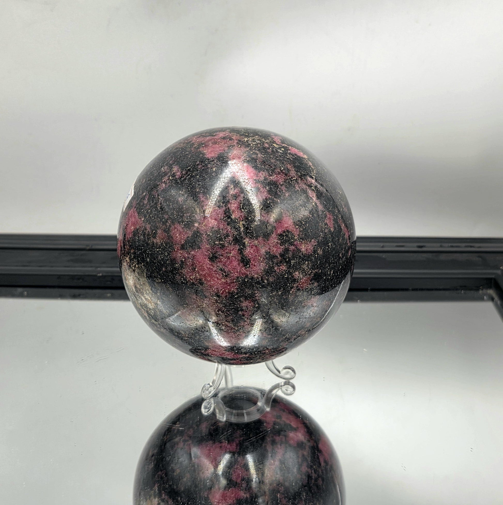 large rhodonite sphere showcasing vivid pink and black contrasts.

