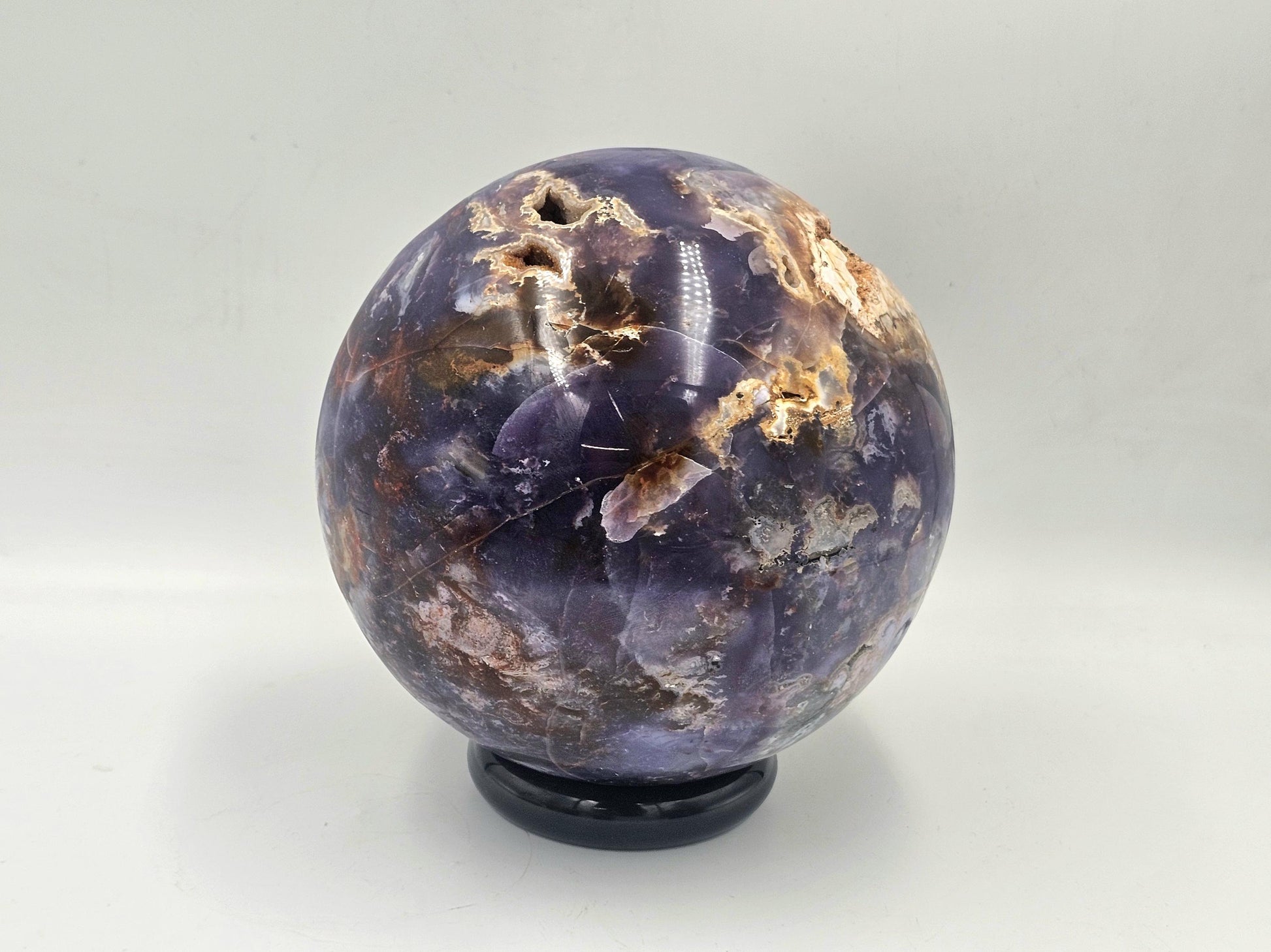 large violet agate sphere on a wooden stand for home or office decoration