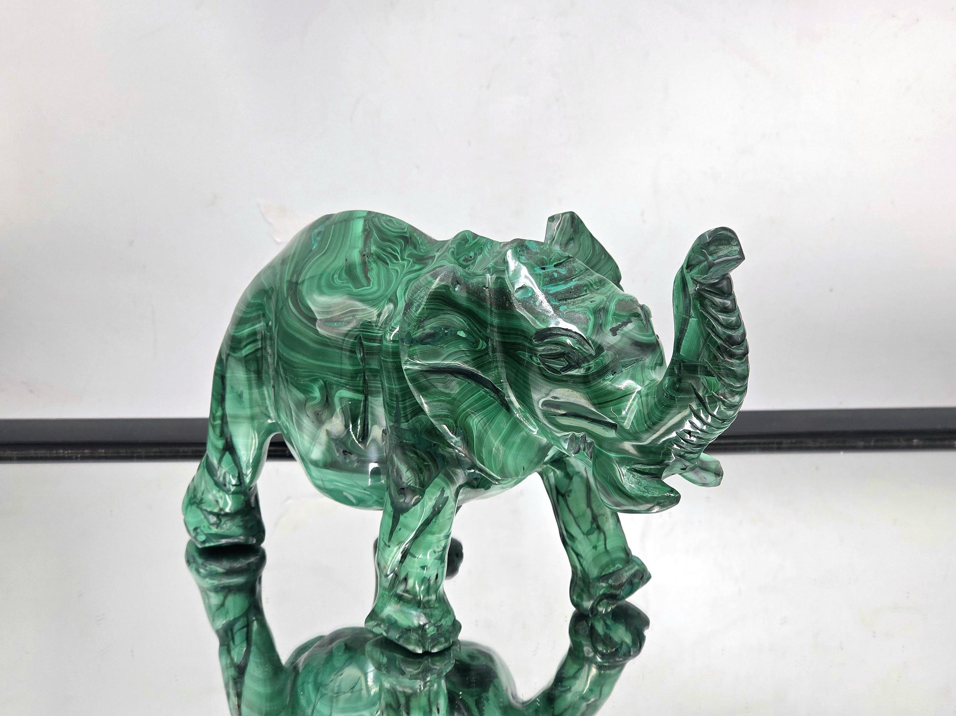 Detailed view of a malachite elephant carving showing striking colour variations and layered green banding.
