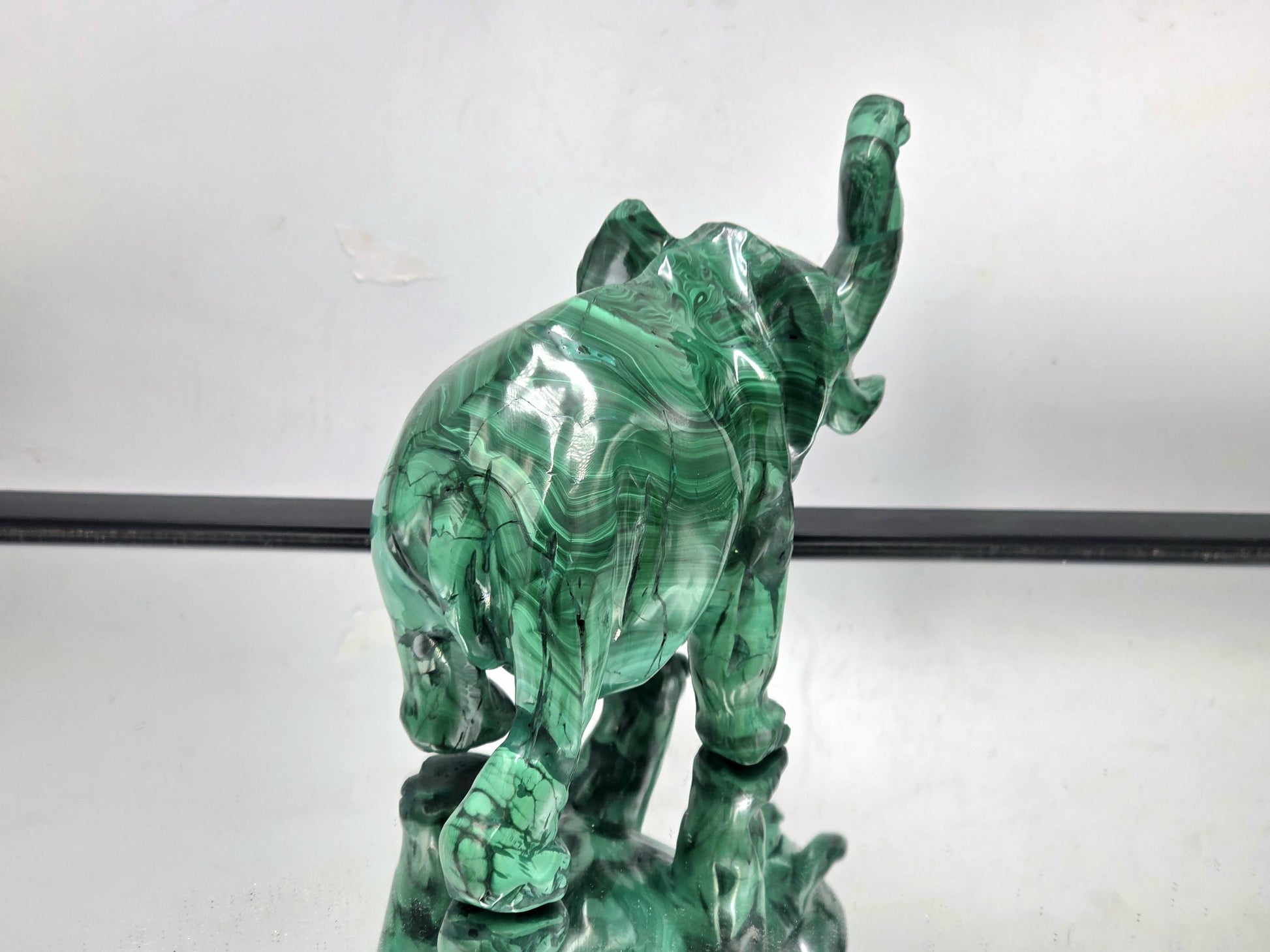 Collection display featuring a large malachite crystal elephant among natural stone carvings and mineral specimens.