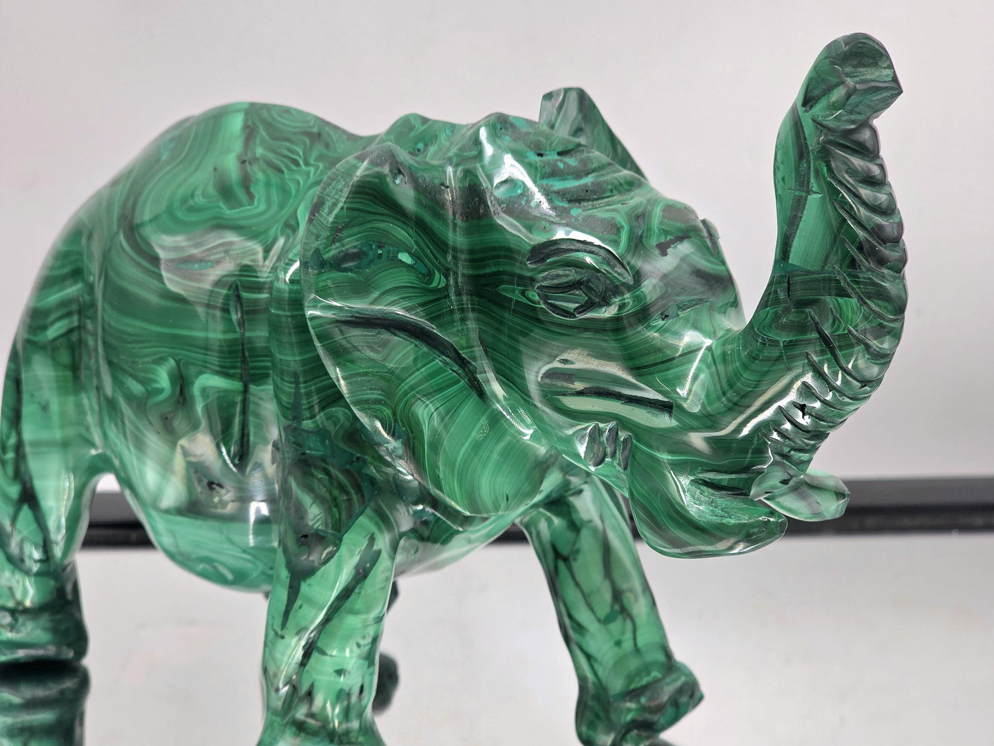 Large malachite crystal elephant sculpture photographed in natural light to highlight its glossy finish and vivid green tones.