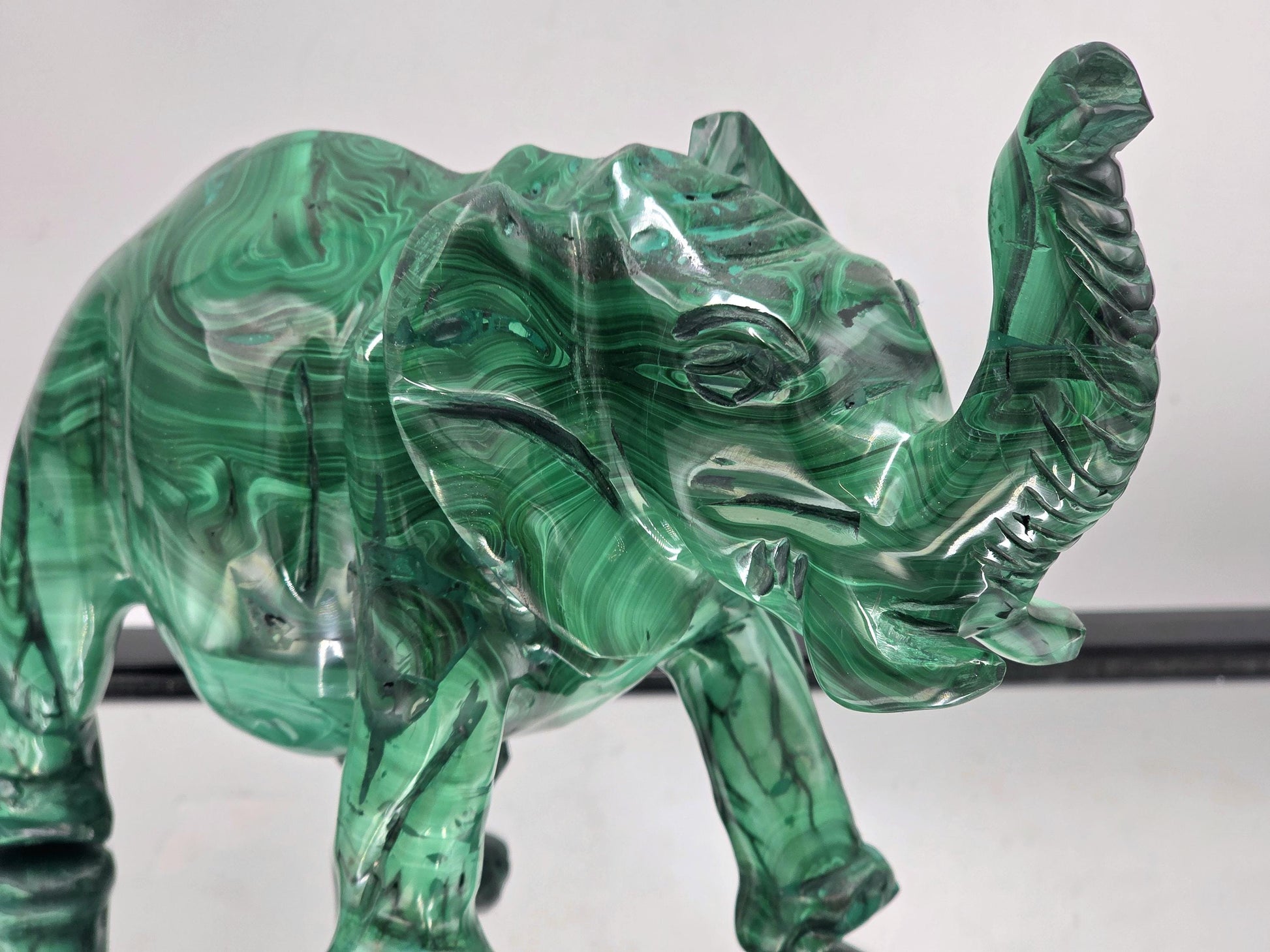 Large malachite crystal elephant sculpture photographed in natural light to highlight its glossy finish and vivid green tones.