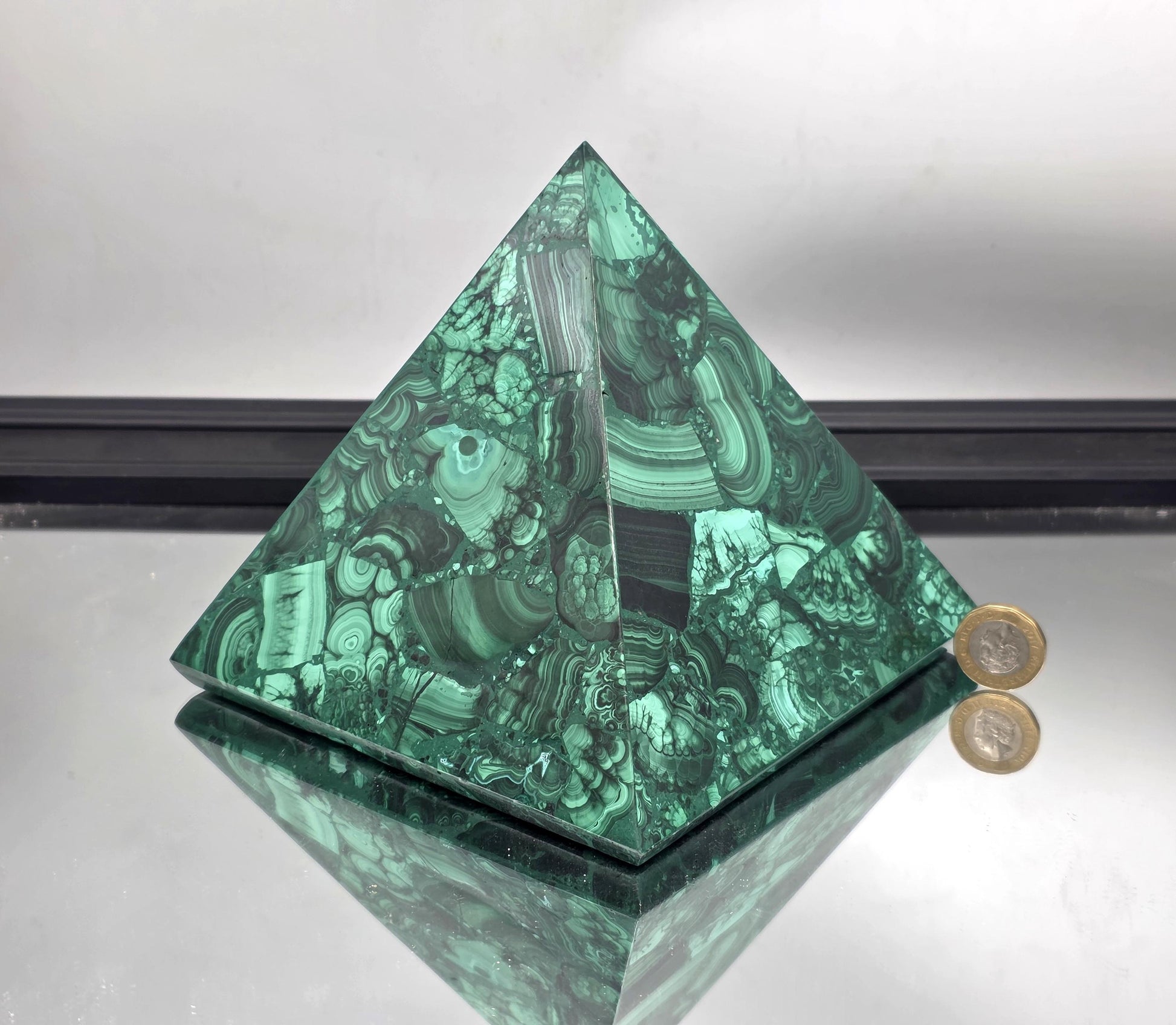 Large and extra large malachite pyramids arranged on an open shelf for layered natural style.