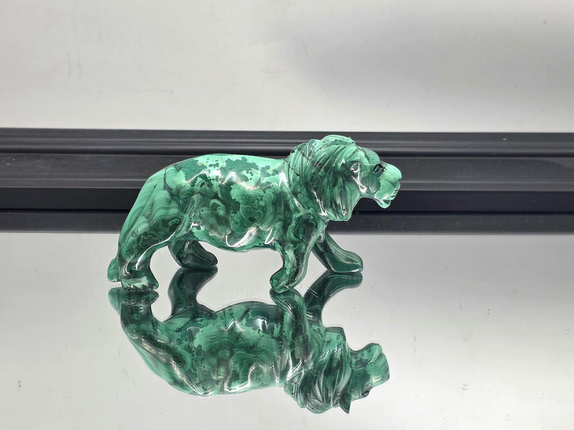 Bold malachite tiger carving displayed on a modern wooden console table.