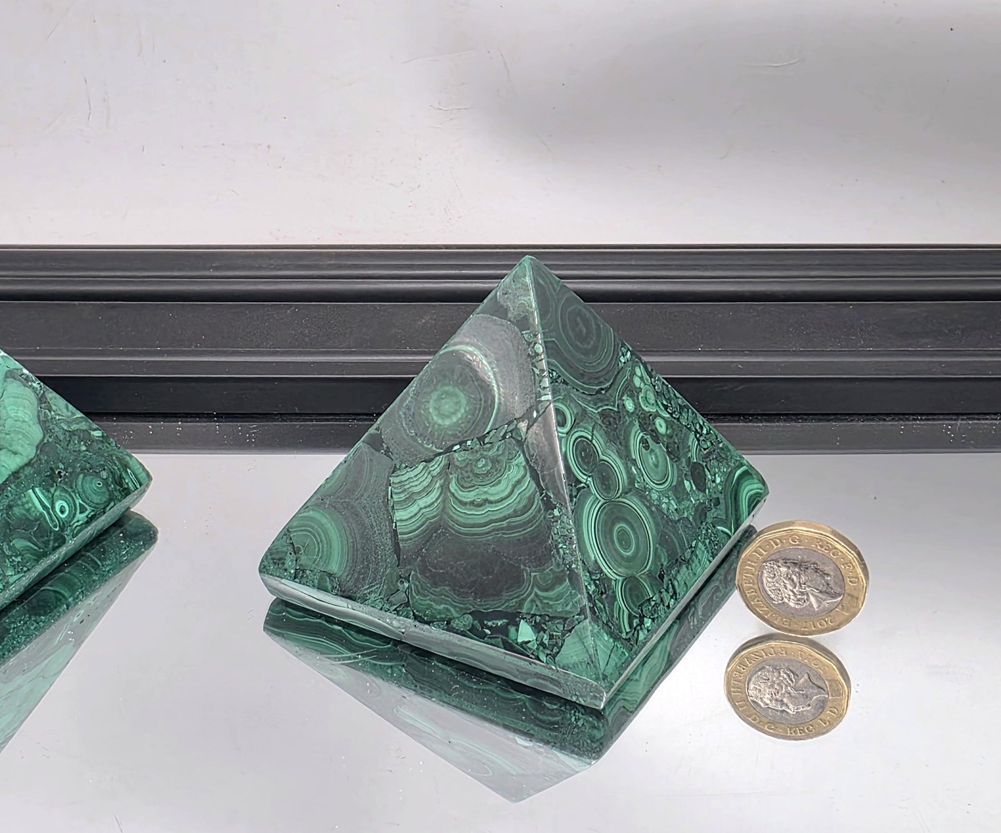 A sculptural green malachite pyramid used as a statement accent in contemporary design.