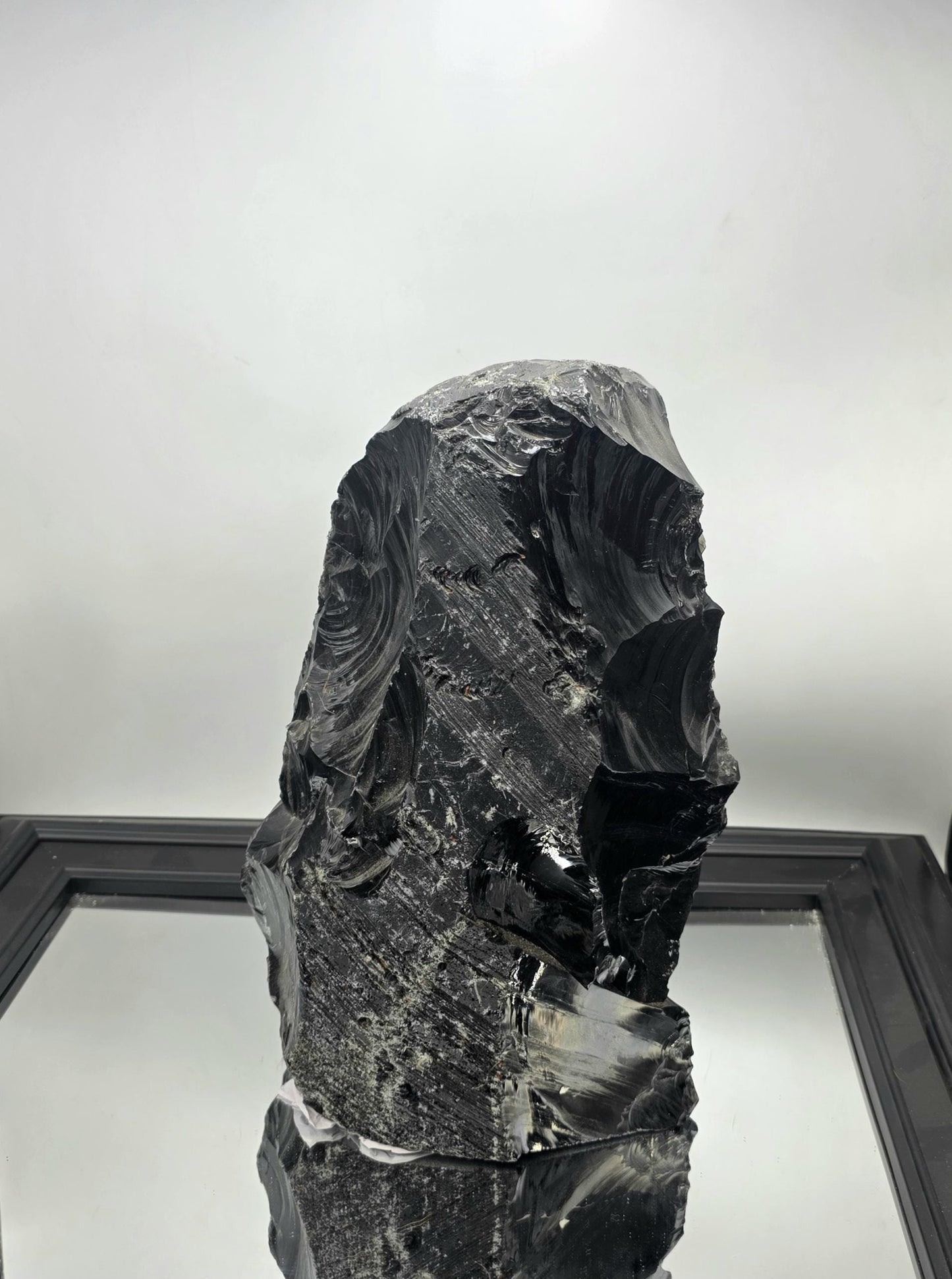 Natural black obsidian crystal accenting a monochrome living room decor setup.