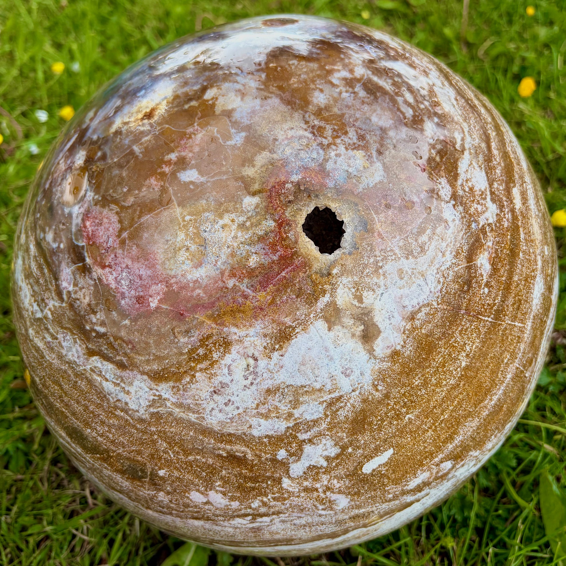 Close-up of a natural sparkling druse crystal cavity on a polished Ocean Jasper sphere.