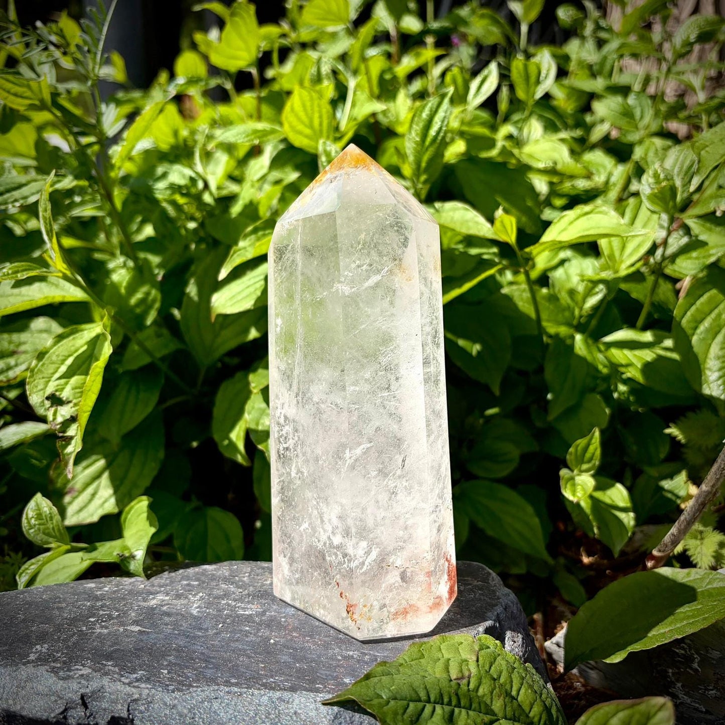Polished clear quartz display crystal with tall prism shape and natural interior textures.
