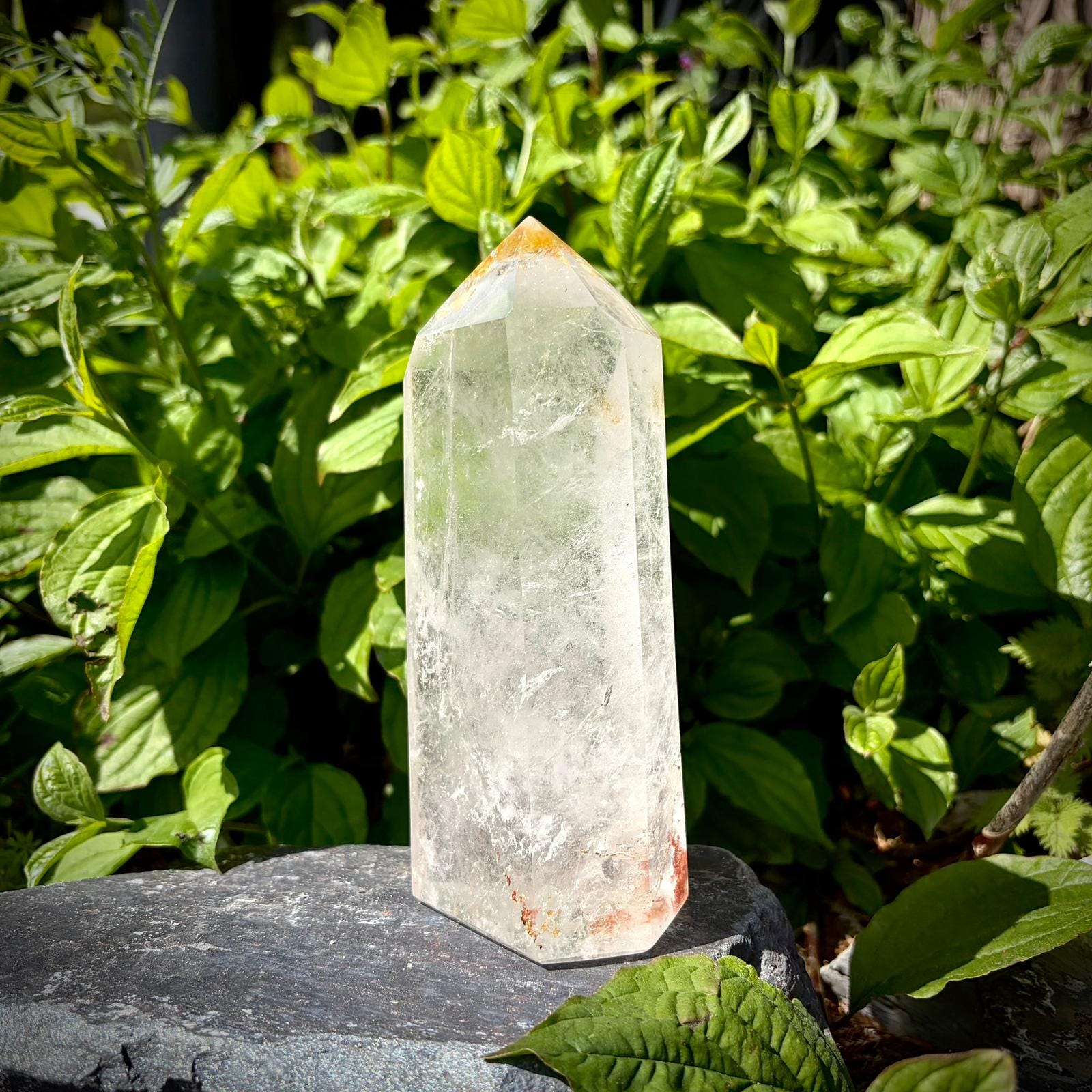 Polished clear quartz display crystal with tall prism shape and natural interior textures.