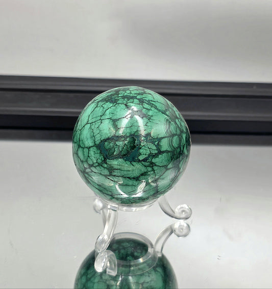 Polished malachite sphere showing vivid green flower banding.