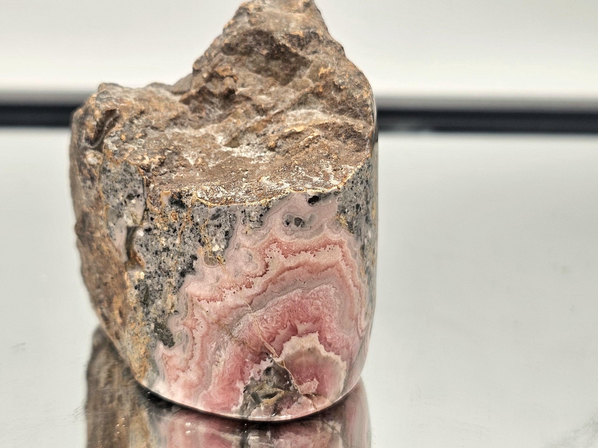Polished Pink Rhodochrosite crystal in its natural matrix, showcasing beautiful pink tones and raw textures.