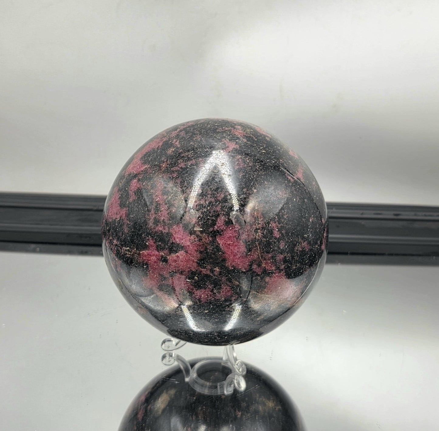 Showpiece-quality rhodonite sphere with rich matrix contrast.