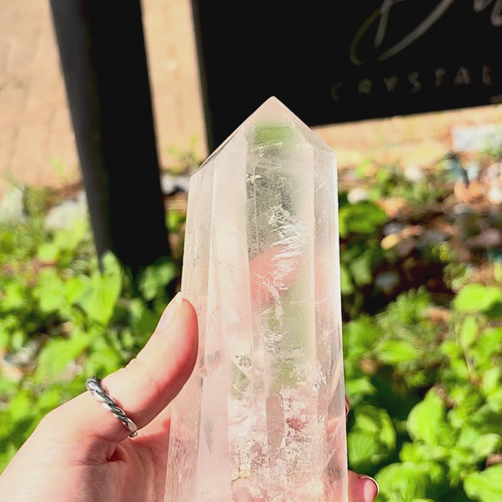 Large clear quartz polished tower with natural veiling, surface markings and decorative form.