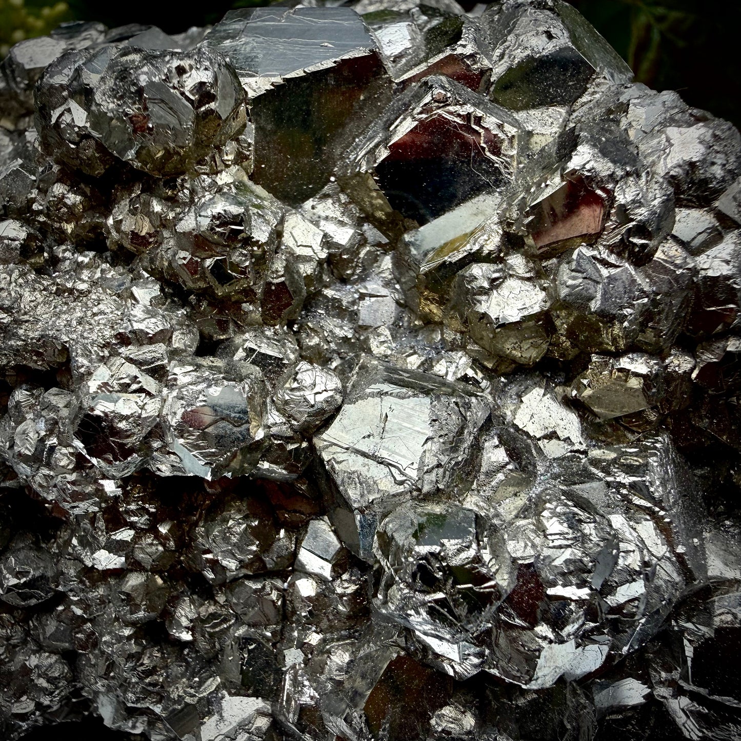 Close-up of multi-faceted geometric pyritohedral crystal formations on a raw Pyrite specimen.