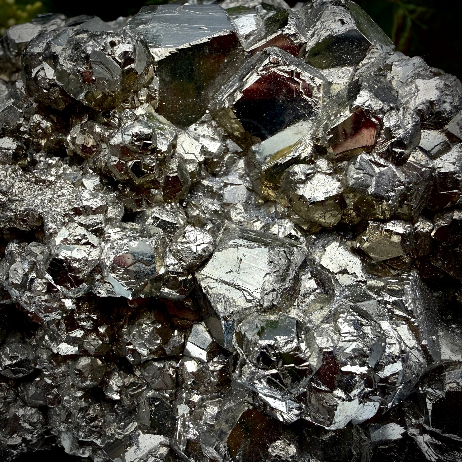 Close-up of multi-faceted geometric pyritohedral crystal formations on a raw Pyrite specimen.
