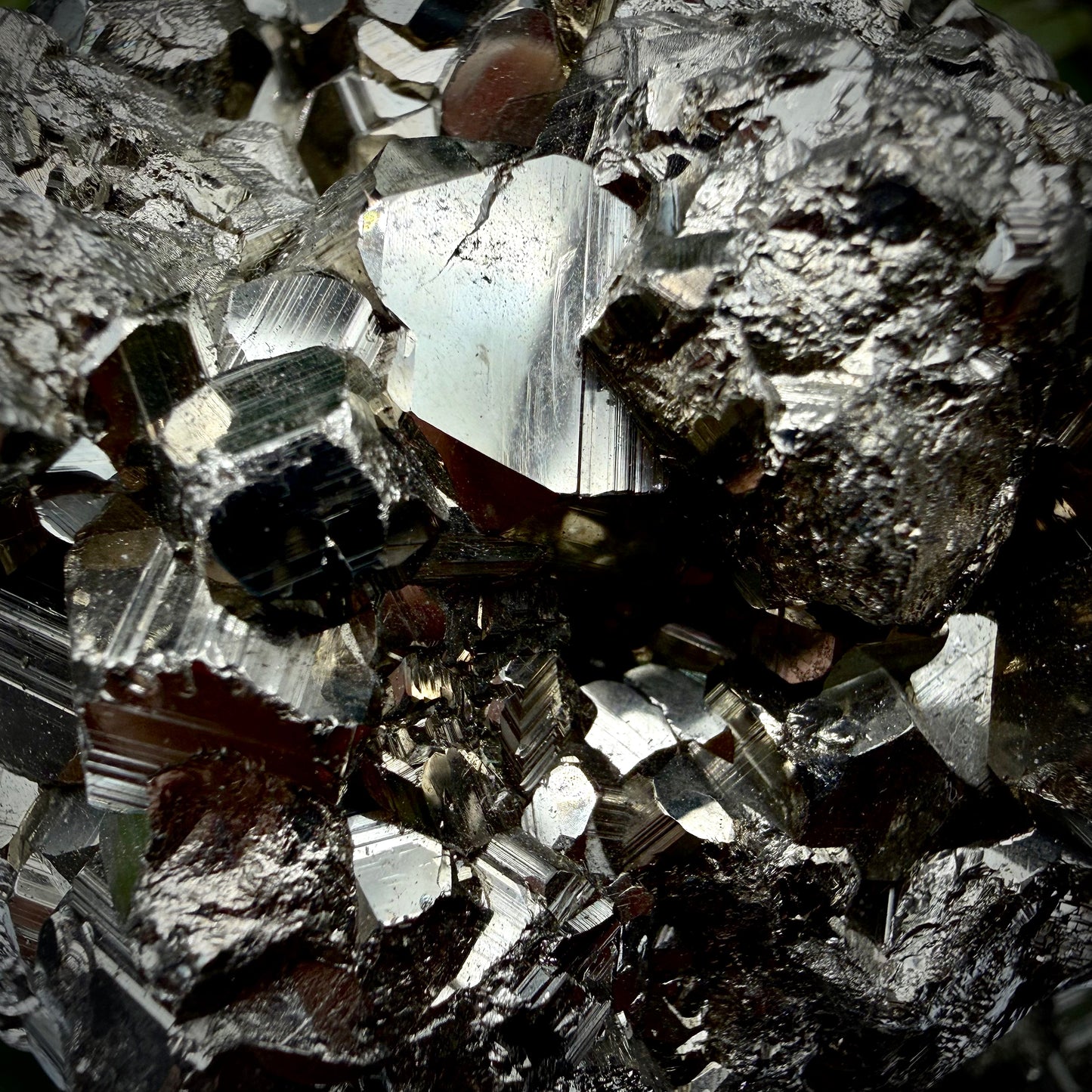 Close-up of multi-faceted geometric pyritohedral crystal formations on a raw Pyrite specimen.