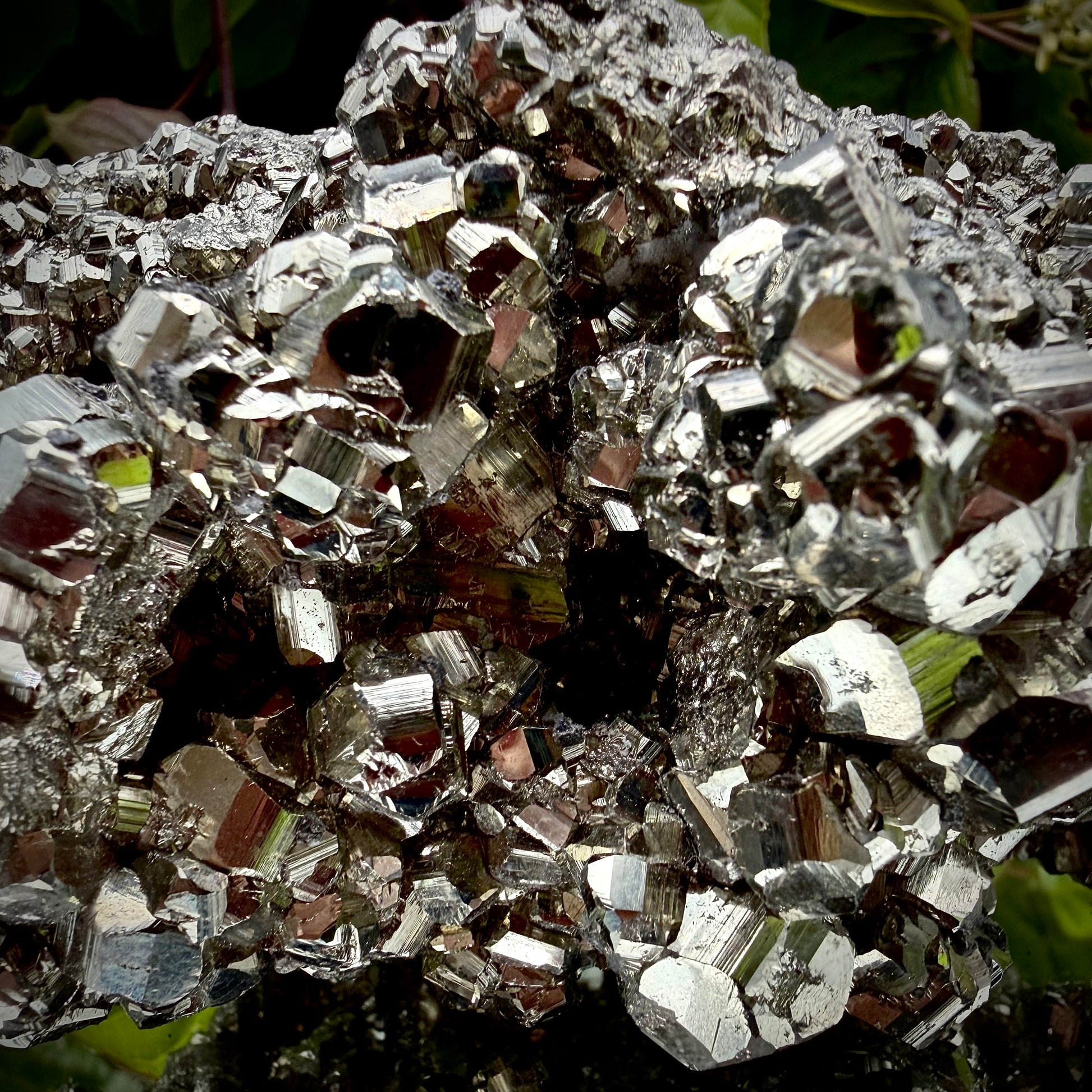 Close-up of multi-faceted geometric pyritohedral crystal formations on a raw Pyrite specimen.