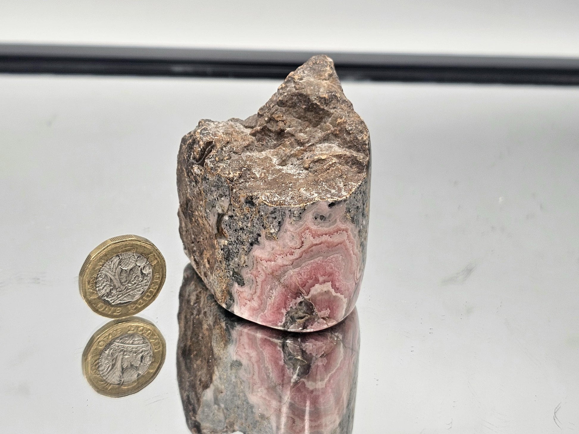 Stunning Pink Rhodochrosite in its natural matrix, emphasizing the contrast between polished and raw elements.