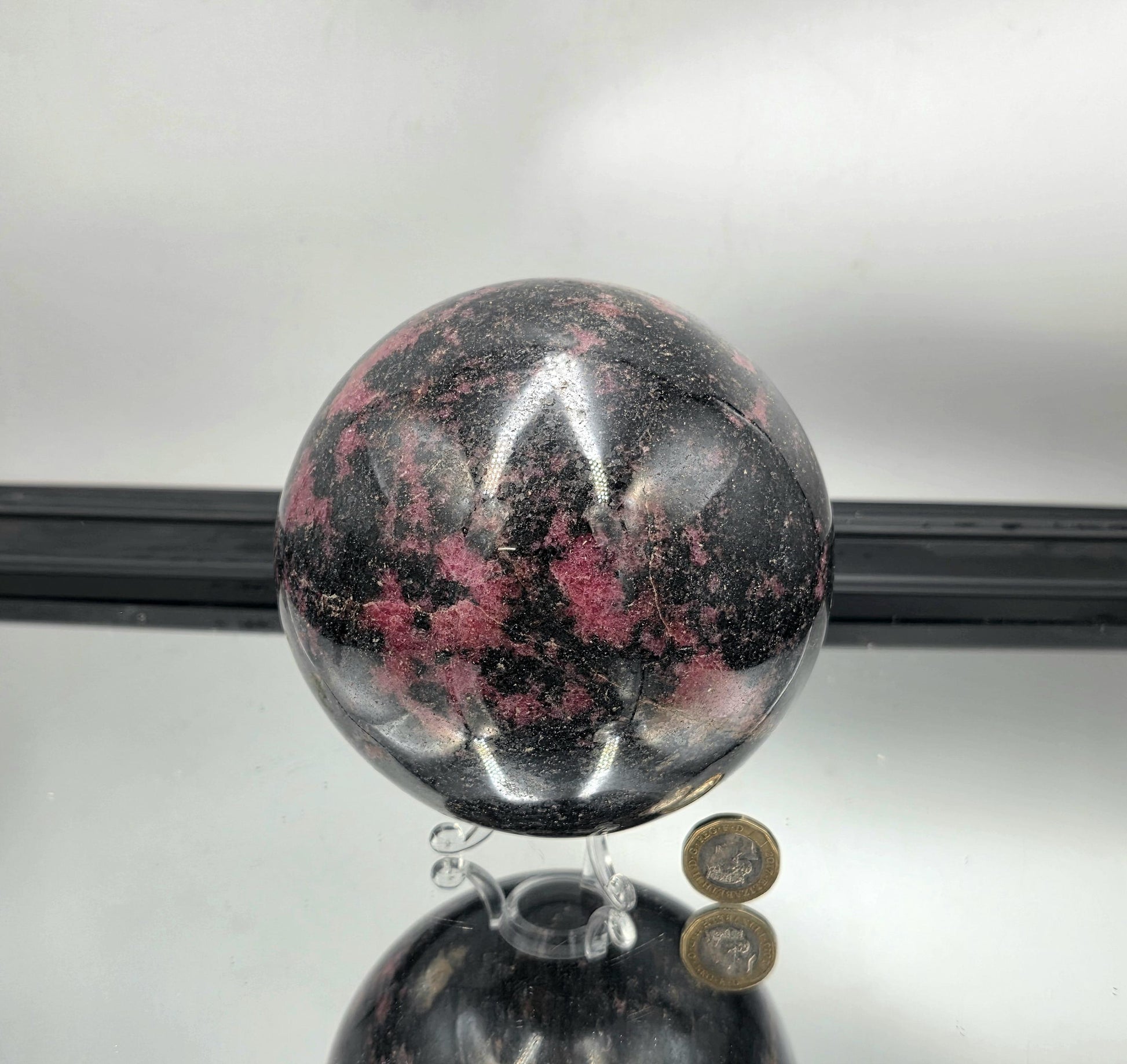 A blend of natural pinks and blacks in a smooth rhodonite ball.