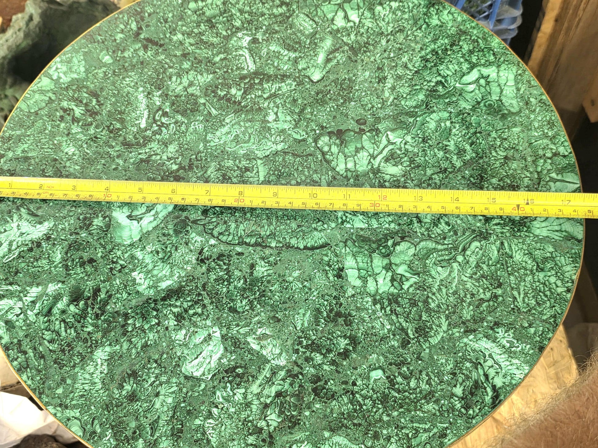 Round green malachite crystal table with natural copper carbonate patterns and elegant brass trim.
