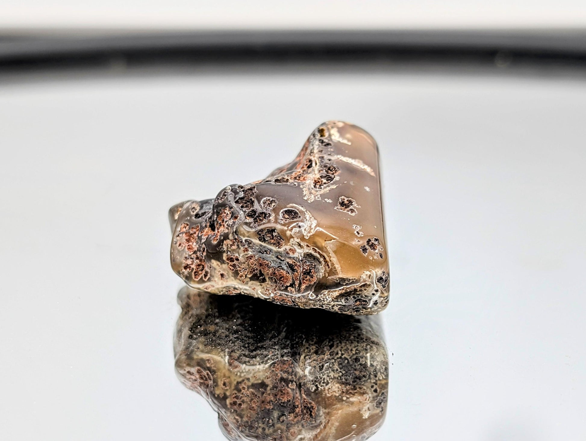 Tumbled agate stone exhibiting natural banding.
