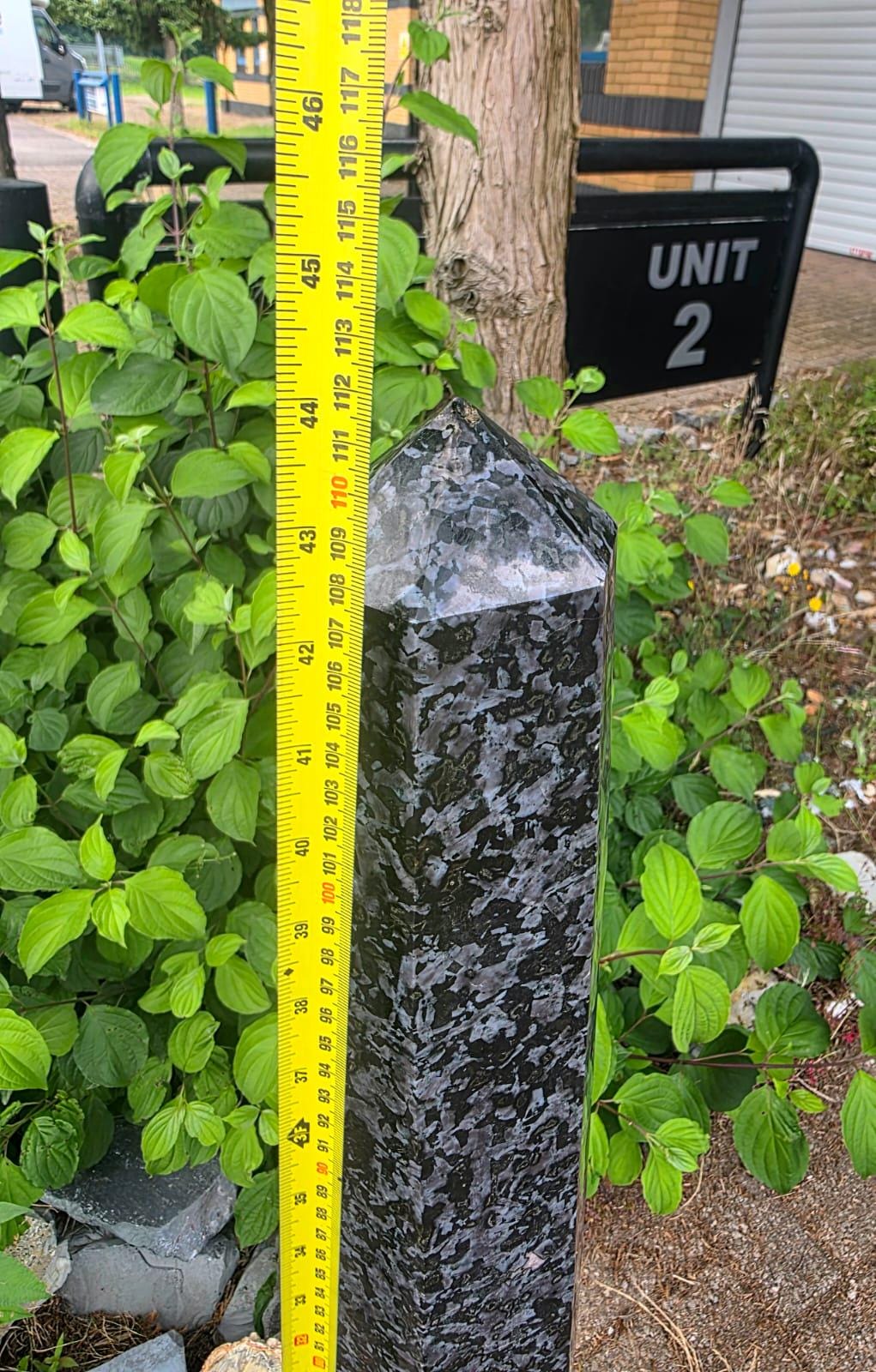 Side view of a large polished Indigo Gabbro tower with a six-sided prism shape.